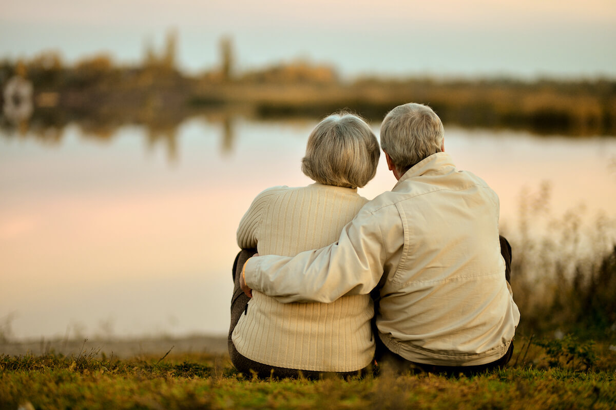 senior couple sitting in summer near lake during sunset_Lakeshore Senior Living