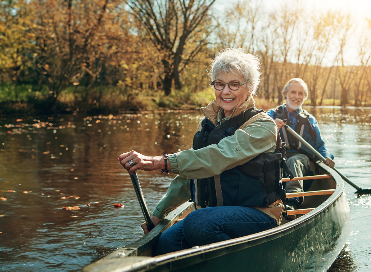 A senior couple smile as they kayak on Lake Guntersville, embracing the elements of nature to boost their mental health.