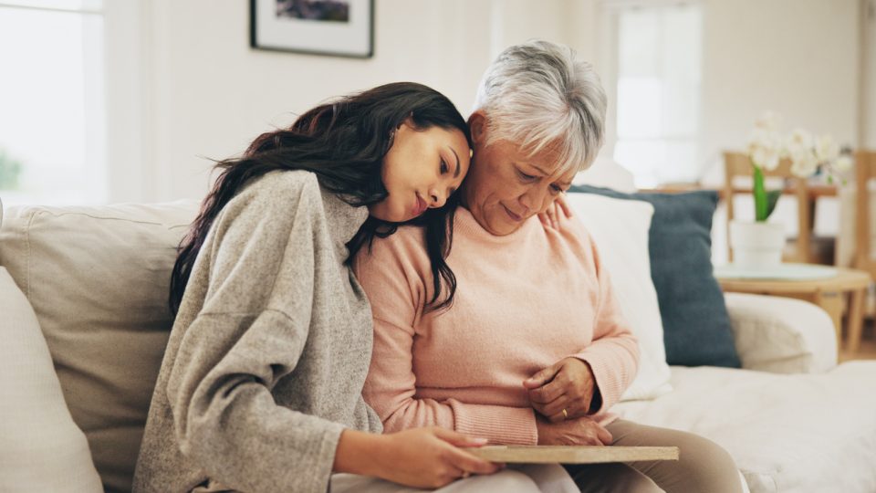 Daughter resting head on mother’s shoulder, showing signs of caregiver burnout due to her mother’s diagnosis of dementia.