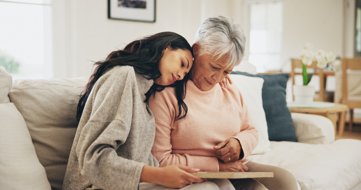 Daughter resting head on mother’s shoulder, showing signs of caregiver burnout due to her mother’s diagnosis of dementia.