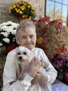 A senior woman holds her dog outside of a senior living community