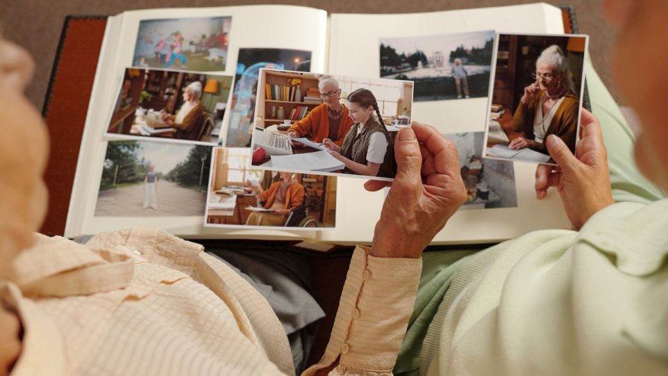 A grandmother shares photos in a scrapbook of her favorite memories with her grandchild.