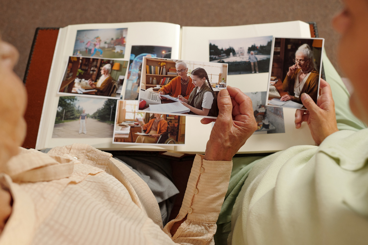A grandmother shares photos in a scrapbook of her favorite memories with her grandchild.