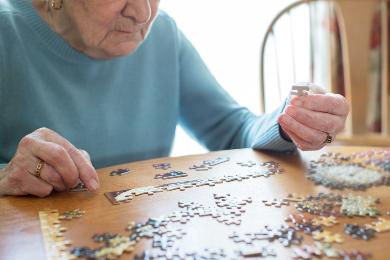 An elderly woman relaxes with a jigsaw puzzle at home in an effort to encourage mental stimulation.